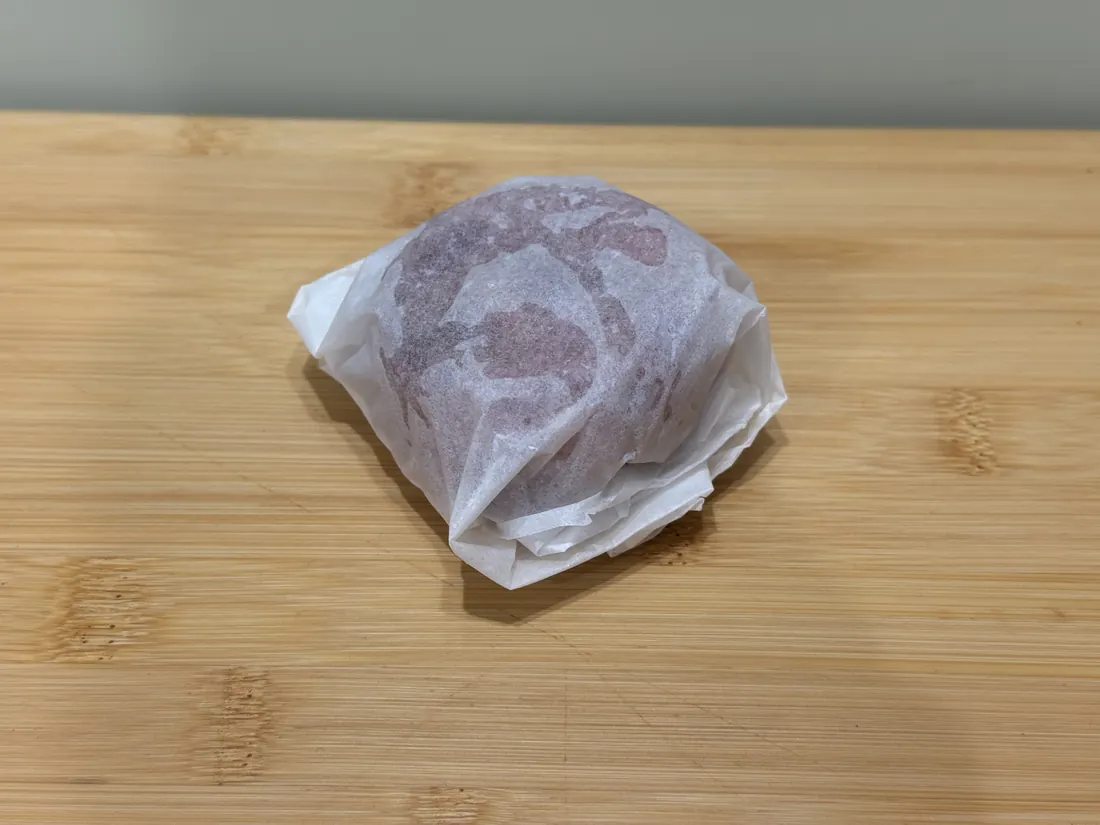 A frozen Cats That Raw puck wrapped in parchment paper